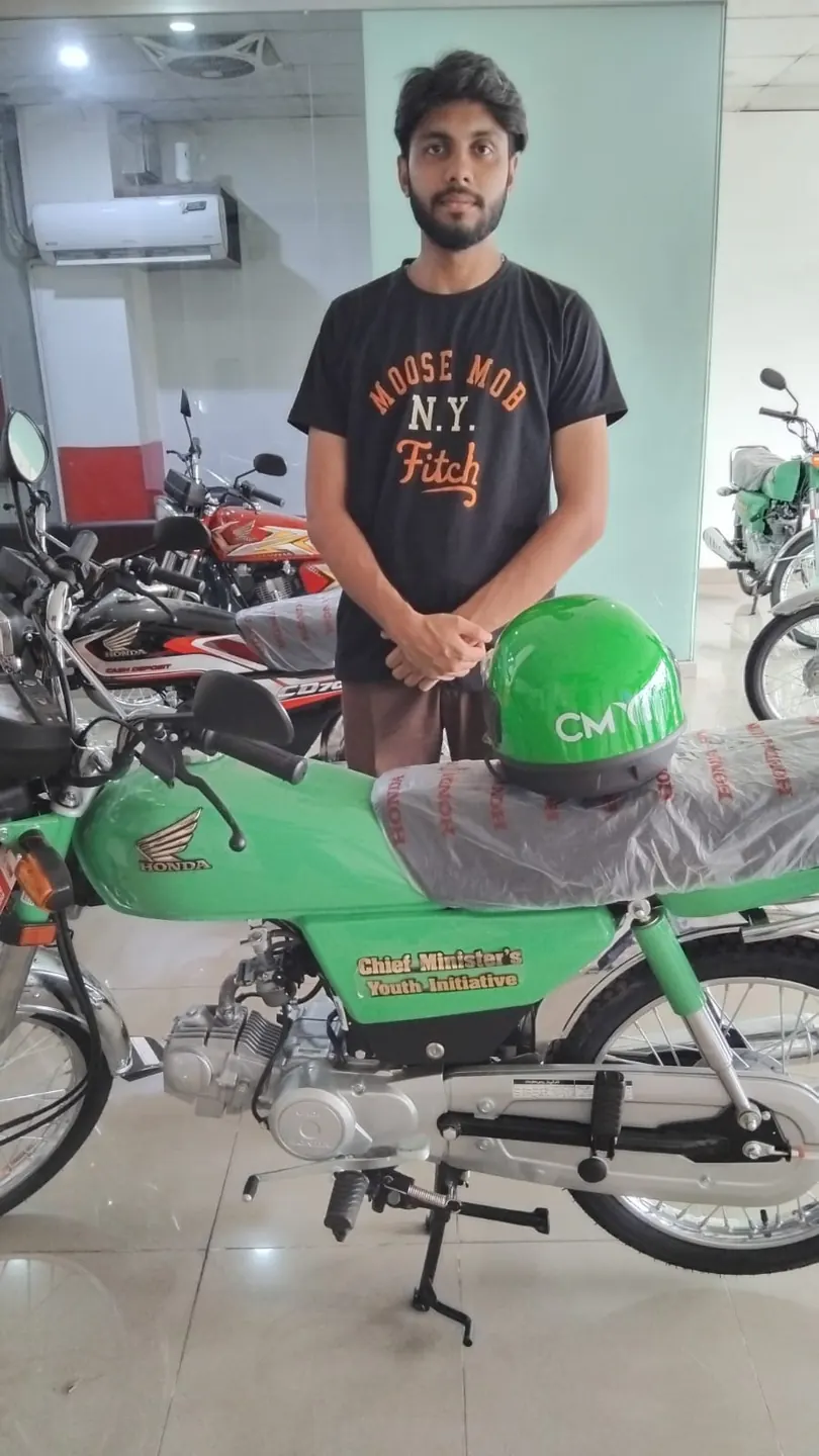 Student standing with a green motorcycle under the government student scheme
